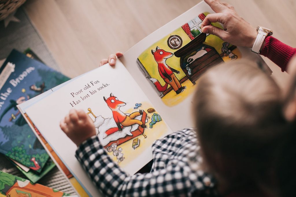 Baby and adult reading a picture book