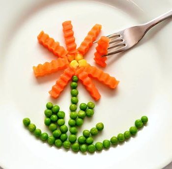 Carrots and peas on plate in the shape of a flower