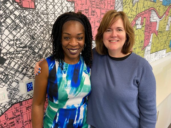 Ilham Askia, CEO of the East Lake Foundation, and Carol Naughton, CEO of Purpose Built Communities, in a conference room wallpapered with red-lining maps.